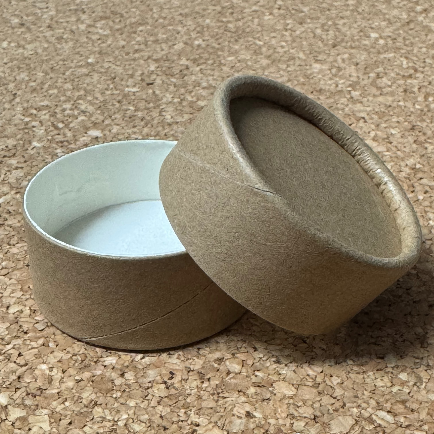 Kraft pot with Kraft lid on a cork surface.