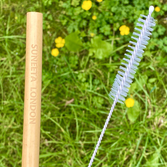 reusable bamboo straw and cleaning brush with text suneeta london on green grass